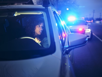A driver pulled over by a police car at night