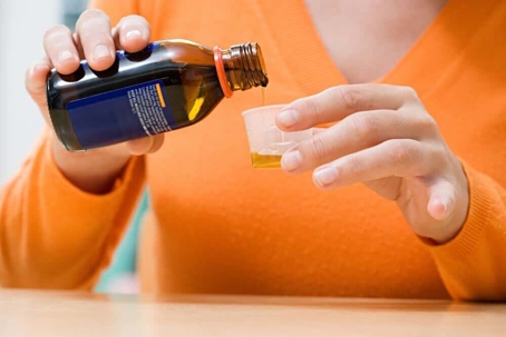 woman pouring cough syrup