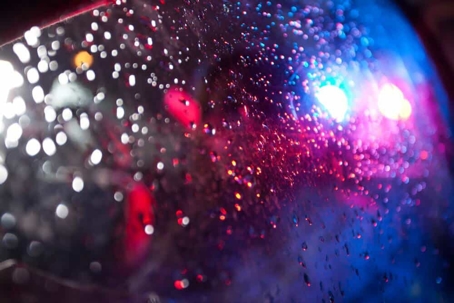 Police car lights reflected in a car window wet with rain